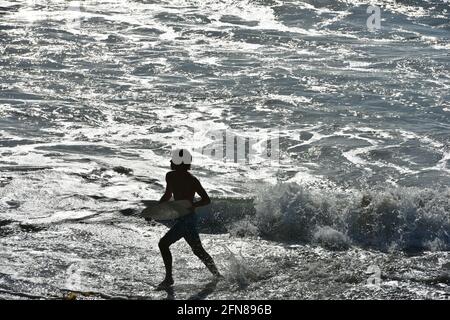 Malerische Landschaft mit einem Surfer, der mit seinem Surfbrett in die Brandung am Ufer des Oceanside Beach in Südkalifornien, USA, läuft. Stockfoto