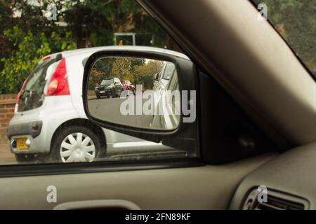 Blick vom Fahrersitz aus aus aus dem Beifahrerfenster mit dem Bild von Tür, Flügel, Spiegel und einem auf der anderen Straßenseite geparkten Auto Stockfoto