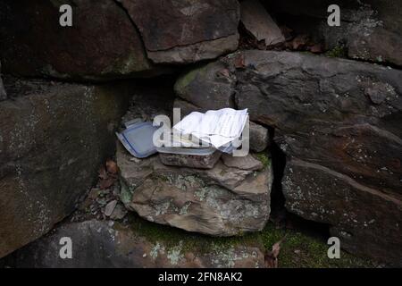 Ein gefundener Geocache-Container, der in einer Wand in Wigan, Greater Manchester, versteckt ist. Stockfoto