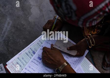 Tehatta, Westbengalen, Indien. Mai 2021. Das Coronavirus ist in das ländliche Indien eingedrungen. Als Quarantänezentrum in einer Dorfgrundschule erhalten die Schüler in einem nahe gelegenen Haus der Schule im Dorf Nabin Nagar Schuhe, die von der Regierung Westbengals jährlich verteilt werden. Die Schuhe der Schüler wurden ihren Eltern aufgrund der Bedrohung durch das Coronavirus übergeben. Die meisten von ihnen sind Hüter, die nicht so gut ausgebildet sind. Das Programm wird mit Vorsicht und Sicherheit durchgeführt, mit sozialer Distanzierung und der Verwendung von Händedesinfektionsmittel. Stockfoto