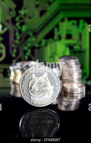 Dogecoin DOGE Kryptowährung Token Münze gegen Stapel von Münzen und Leiterplattenmuster Stockfoto