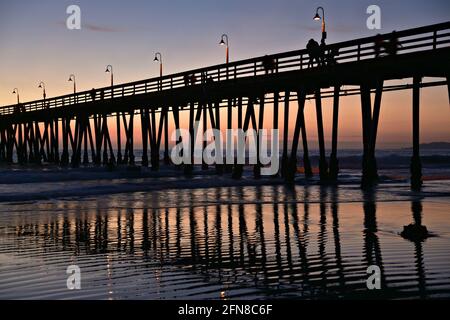 Sonnenuntergangs-Seeseite mit Panoramablick auf den Oceanside Beach Pier und People Silhouetten in San Diego, Südkalifornien, USA. Stockfoto