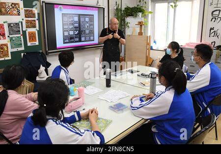 (210515) -- PEKING, 15. Mai 2021 (Xinhua) -- Wang Kun spricht in einer Klasse an der Pekinger Jianxiang Spezialschule, in Peking, Hauptstadt von China, am 13. Mai 2021. Wang Kun, 47, ist eine hörgeschädigte Kunstlehrerin an der Pekinger Jianxiang Spezialerziehungsschule. Die Arbeit als Speziallehrerin war eine Herausforderung. Wang Kun lernt, liest und kommuniziert mit anderen Lehrern, um seine einzigartigen Lehrmethoden zu etablieren. „im Unterricht verwende ich meist anschauliche Beispiele und Vergleiche, um komplizierte Kunsttheorien zu erklären. Gleichzeitig würde ich den Studenten Bücher und Kunstwerke empfehlen Stockfoto