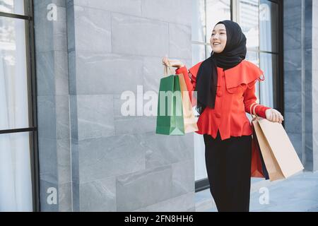 Shopping Arab Muslim Erwachsene Frau im Schleier hijab Kleidung mit Taschen zu Fuß in der Stadt Straße genießen glückliches Lächeln. Stockfoto