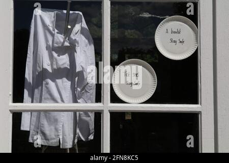 Die Jacke des Küchenchefs und die Schilder im Fenster wegen der erzwungenen Schließung der Restaurants als Sicherheitsmaßnahme zur Bekämpfung des Corona-Virus. Text=„See you soon, stay Safe“ Stockfoto