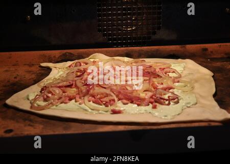 Rustikales, hausgemachtes Flammkuchen, das im Ofen gebacken wird Stockfoto