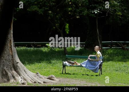 Bukarest, Rumänien. Mai 2021. Eine Frau genießt die Sonne in einem Park in Bukarest, Rumänien, 15. Mai 2021. Der rumänische Premierminister Florin Citu sagte, die Regierung habe am Freitag eine Entscheidung getroffen, die Einschränkungen im Zusammenhang mit dem Coronavirus ab Samstag schrittweise zu lockern. Ab Samstag wird die Sperrstunde in der Nacht aufgehoben, und die obligatorischen Maskenregeln werden nur in geschlossenen öffentlichen Räumen und überfüllten öffentlichen Bereichen, einschließlich Märkten, öffentlichen Verkehrsmitteln und Arbeitsplätzen, angewendet. Quelle: Cristian Cristel/Xinhua/Alamy Live News Stockfoto