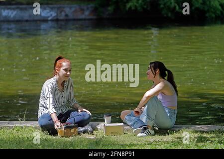 Bukarest, Rumänien. Mai 2021. Menschen genießen die Sonne in einem Park in Bukarest, Rumänien, 15. Mai 2021. Der rumänische Premierminister Florin Citu sagte, die Regierung habe am Freitag eine Entscheidung getroffen, die Einschränkungen im Zusammenhang mit dem Coronavirus ab Samstag schrittweise zu lockern. Ab Samstag wird die Sperrstunde in der Nacht aufgehoben, und die obligatorischen Maskenregeln werden nur in geschlossenen öffentlichen Räumen und überfüllten öffentlichen Bereichen, einschließlich Märkten, öffentlichen Verkehrsmitteln und Arbeitsplätzen, angewendet. Quelle: Cristian Cristel/Xinhua/Alamy Live News Stockfoto