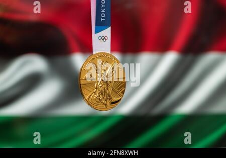 25. April 2021 Tokio, Japan. Goldmedaille der XXXII. Olympischen Sommerspiele 2020 in Tokio auf dem Hintergrund der ungarischen Flagge. Stockfoto