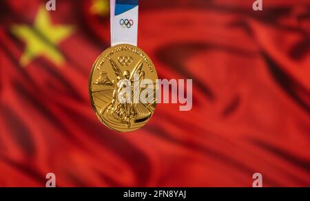 25. April 2021 Tokio, Japan. Goldmedaille der XXXII. Olympischen Sommerspiele 2020 in Tokio auf dem Hintergrund der chinesischen Flagge. Stockfoto