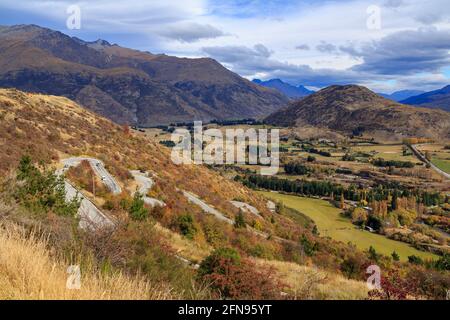 Die steile, kurvenreiche Straße entlang der Crown Range in der Nähe von Queenstown, Neuseeland, die als „Zig Zag“ bezeichnet wird, mit einem malerischen Blick auf das Tal darunter Stockfoto