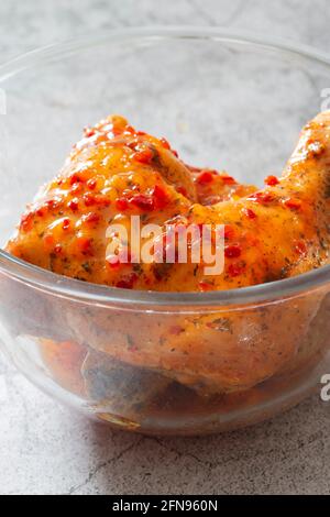 Hähnchen mit Piri- oder Peri-Marinade-Sauce in einer Glasschüssel. Auf einem konkreten Hintergrund Stockfoto