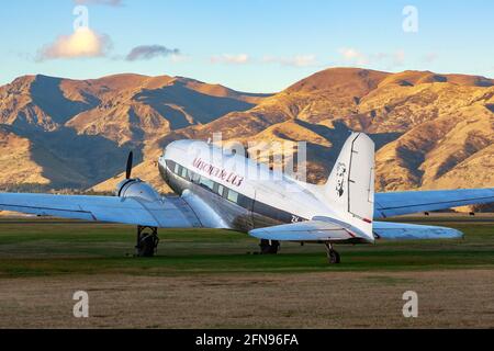 Ein Douglas DC-3 aus den 1930er Jahren auf einem Feld in Wanaka, Neuseeland, mit einer Bergkette im Hintergrund Stockfoto