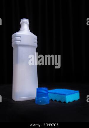 Blauer Schwamm mit einer Flasche Reinigungsmittel auf schwarzem Hintergrund. Stockfoto