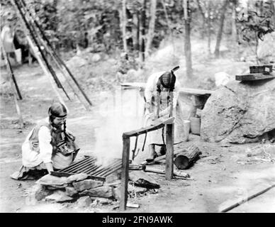 Pfadfinderin. Zwei Mädchen Scouts Gebäude ein Feuer im Lager, c. 1912 Stockfoto