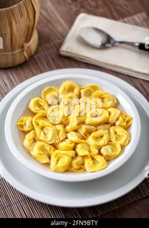 Italienische Tortellini in der Brühe auf einem Teller. Stockfoto