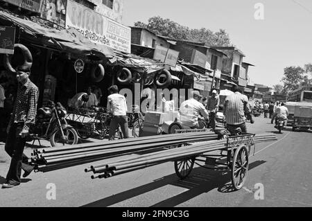 Eisenstangen, die auf einem Dreirad druch die Strassen von Ahmedabad gefahren werden auf einem Fahrrad durch die Straßen von Ahmedab getragen Stockfoto