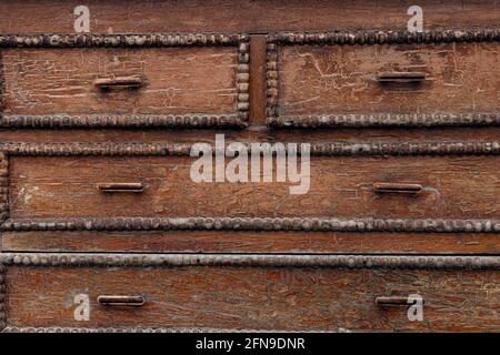 Alte gerissene Kommode aus Holz. Hintergrund mit braunen Rissen auf einer Kommode aus Holz mit rostigen Griffen. Stockfoto