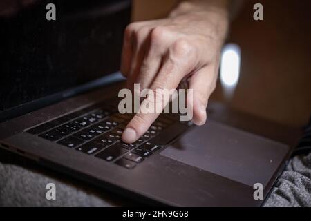 Die Hand eines Mannes drückt mit dem Finger auf die Tastatur eines Laptops. Stockfoto