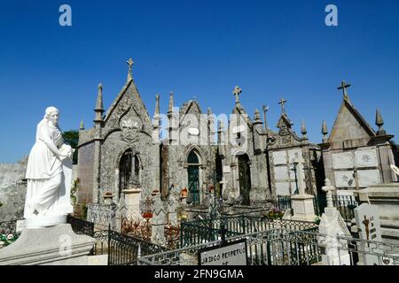 Statue der Jungfrau Maria und Mausoleen aus grauem Granit auf dem Friedhof neben der Kirche und dem Kloster Santo Antonio, Caminha, Provinz Minho, Portugal Stockfoto