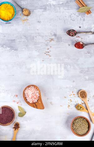 Bunte Gewürze auf der Schüssel und Löffel auf dem Steintisch. Draufsicht Stockfoto