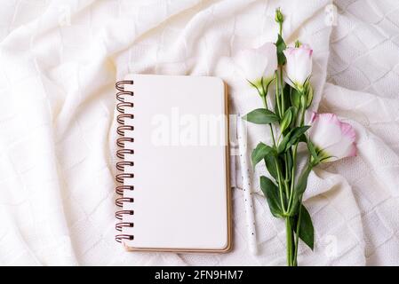 Öffnen Sie leeres Notizbuch und Blumenstrauß eustoma auf Decke Hintergrund. Schöne Grußkarte im Vintage-Stil. Flach liegend. Stockfoto