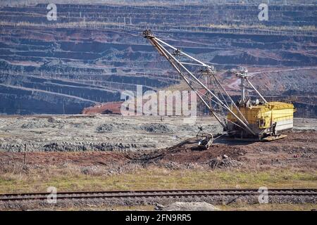 Wanderbagger, Eisenbahnstrecke auf dem Hintergrund eines Teils des Eisenerzbruchs. Hintergrund. Kopieren Sie den Speicherplatz. Stockfoto