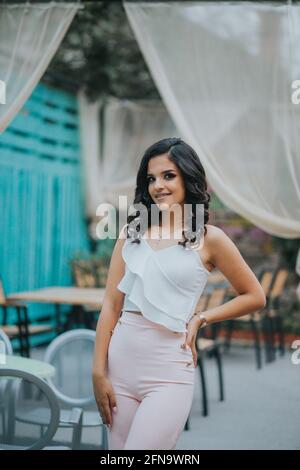 Wunderschöne Hündin in einem eleganten rosa-weißen Outfit Hintergrund eines Cafés im Freien Stockfoto