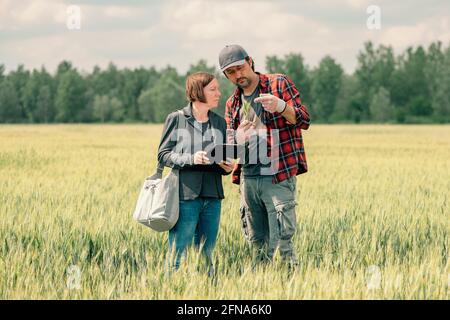 Hypothek Darlehen Officer Unterstützung Landwirt in finanziellen Zuschuss Antragsprozess, Bankier und Landarbeiter in Weizenfeld. Stockfoto