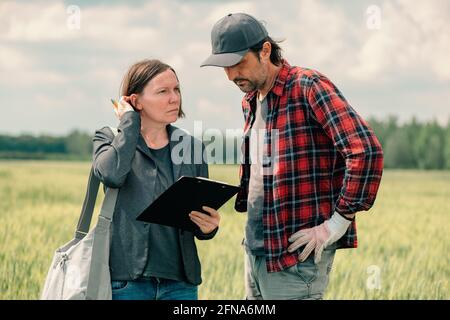 Hypothek Darlehen Officer Unterstützung Landwirt in finanziellen Zuschuss Antragsprozess, Bankier und Landarbeiter in Weizenfeld. Stockfoto