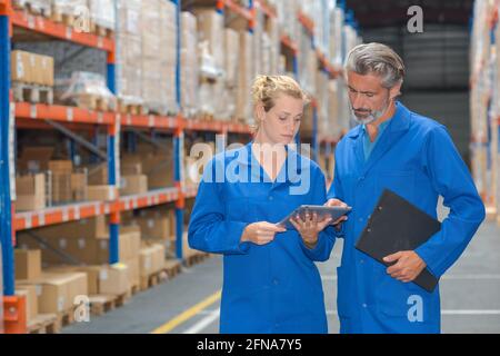 Mann und Frau im Lager mit Klemmbrett und Tablet Stockfoto