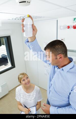 Mann installiert Rauchmelder an der Deckenwand zu Hause Stockfoto