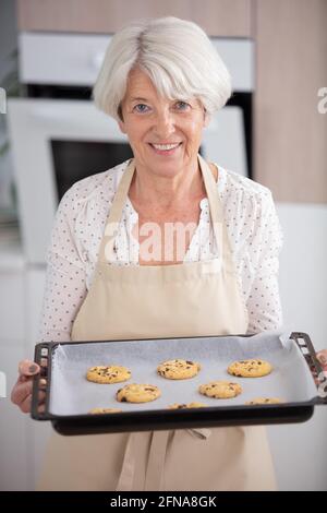 Glückliche, reife Frau, die ein Kekstablett hält Stockfoto