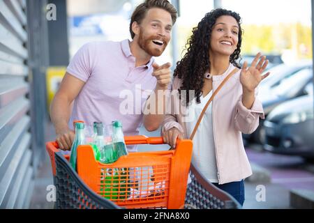 Paar mit einem Einkaufswagen auf dem Parkplatz im Freien Stockfoto