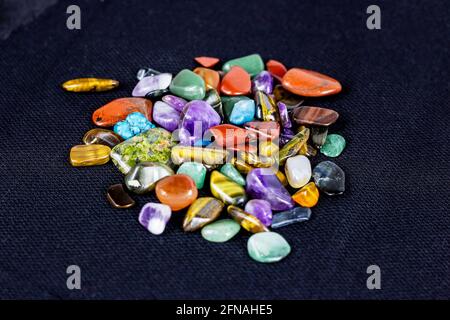 Verschiedene bunte Edelsteine auf dunklem Hintergrund. Steintherapie, spirituelle Heilung, Kristallenergie, Lithotherapie, esoterische Meditation und Zauberkonzept Stockfoto