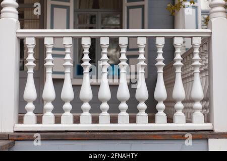 Architektonisches Element des Balusters. Zäune auf der Veranda. Stilvoller Holzfußboden. Zu einem Zylinder verarbeitetes Holz. Eine Reihe von sich wiederholenden Haus deta Stockfoto