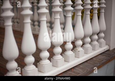 Architektonisches Element des Balusters. Zäune auf der Veranda. Stilvoller Holzfußboden. Zu einem Zylinder verarbeitetes Holz. Eine Reihe von sich wiederholenden Haus deta Stockfoto