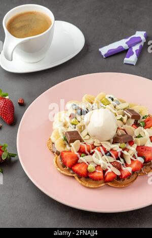 Herzwaffel mit Banane und Erdbeere mit Gummy Candy und Eis darauf. Stockfoto