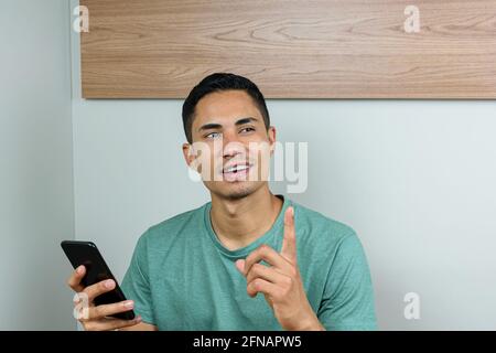 28-jähriger Brasilianer, der ein Smartphone hielt und mir ein Gesicht machte, hatte eine Idee. Stockfoto