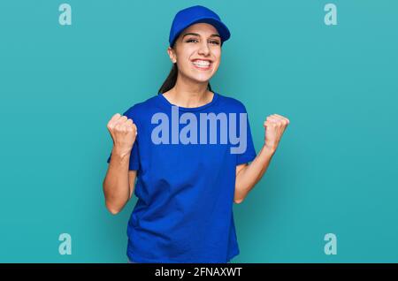 Junge hispanische Mädchen trägt Lieferung Kurier Uniform feiert überrascht und erstaunt über den Erfolg mit erhobenen Armen und offenen Augen. Sieger-Konzept. Stockfoto