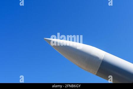 Rakete mit einem Sprengkopf, der im Sonnenlicht auf den blauen Himmel zeigt. Nahaufnahme. Stockfoto