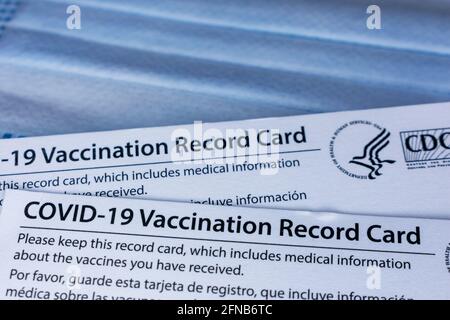 Nahaufnahme. Covid-19 Impfprotokollkarten, ausgestellt von CDC, United States Centers for Disease Control and Prevention, auf einem blauen Einweg-schutzfa Stockfoto