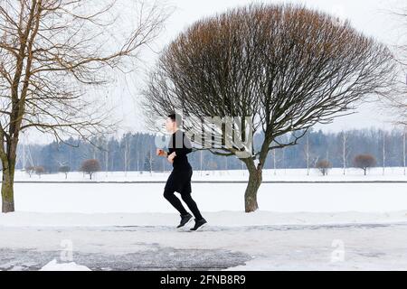 Der junge Mann geht im Winter beim Sport joggen. Stockfoto