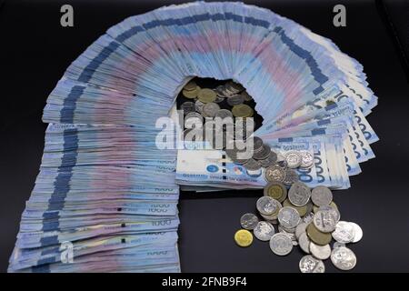 Ein Stapel von eintausend philippinischen Banknoten und Münzen Stockfoto