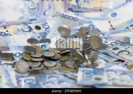 Ein Stapel von eintausend philippinischen Banknoten und Münzen Stockfoto