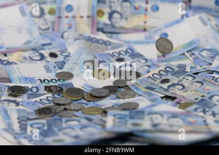 Ein Stapel von eintausend philippinischen Banknoten und Münzen Stockfoto