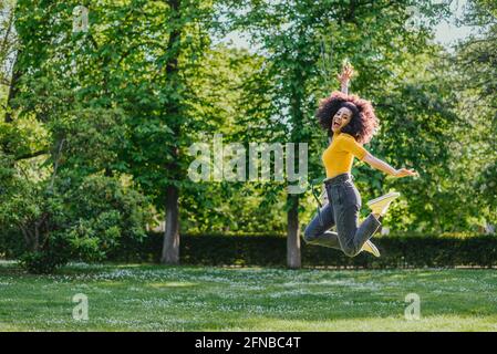 Hübsche Frau, die glücklich in einem Garten springt. Stockfoto