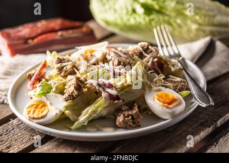 Caesar-Salat mit gekochten Eiern, Speck und Croutons auf einem Teller. Stockfoto