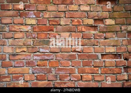 Gebäudewandfassade eines alten Hauses aus gerissenem rotem Backstein. Hintergrund für Design oder Webseite. Stockfoto