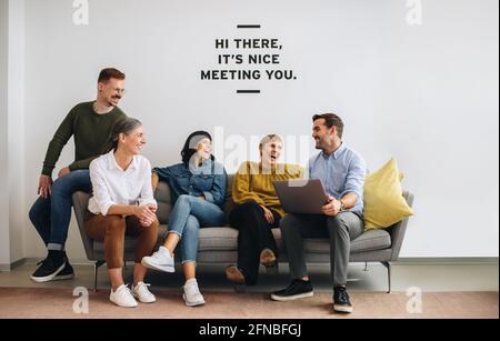 Glückliche Unternehmer sitzen zusammen und teilen Ideen in der Lobby. Kreatives Team lächelt während der Projektarbeit. Stockfoto